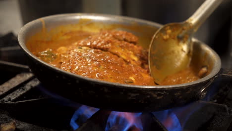 chef bastes whole fish in simmering pan sauce, close up slider slow motion hd