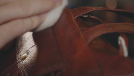 hand polishing brown leather bag - close up