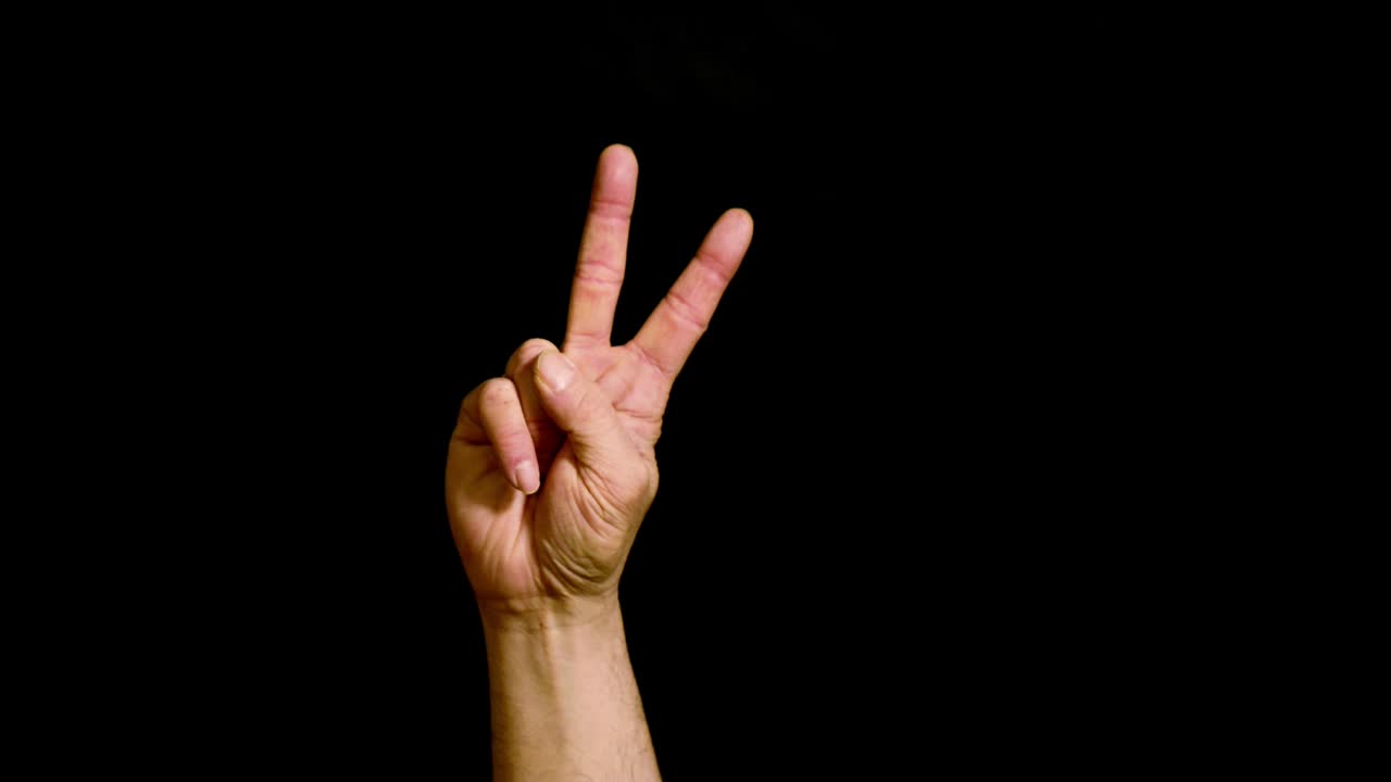 Mano maschile che mostra il numero due su sfondo nero