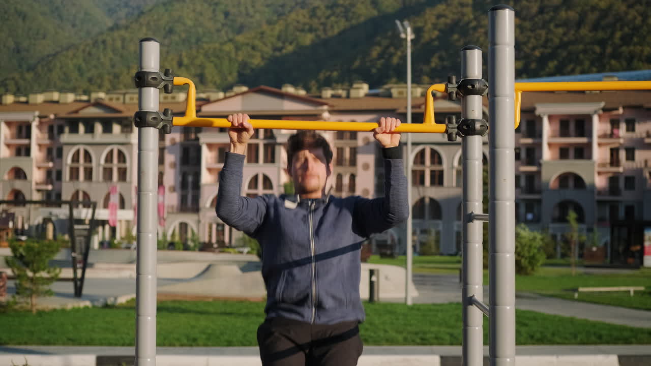 야외 체육관 에서 풀업 을 하는 남자