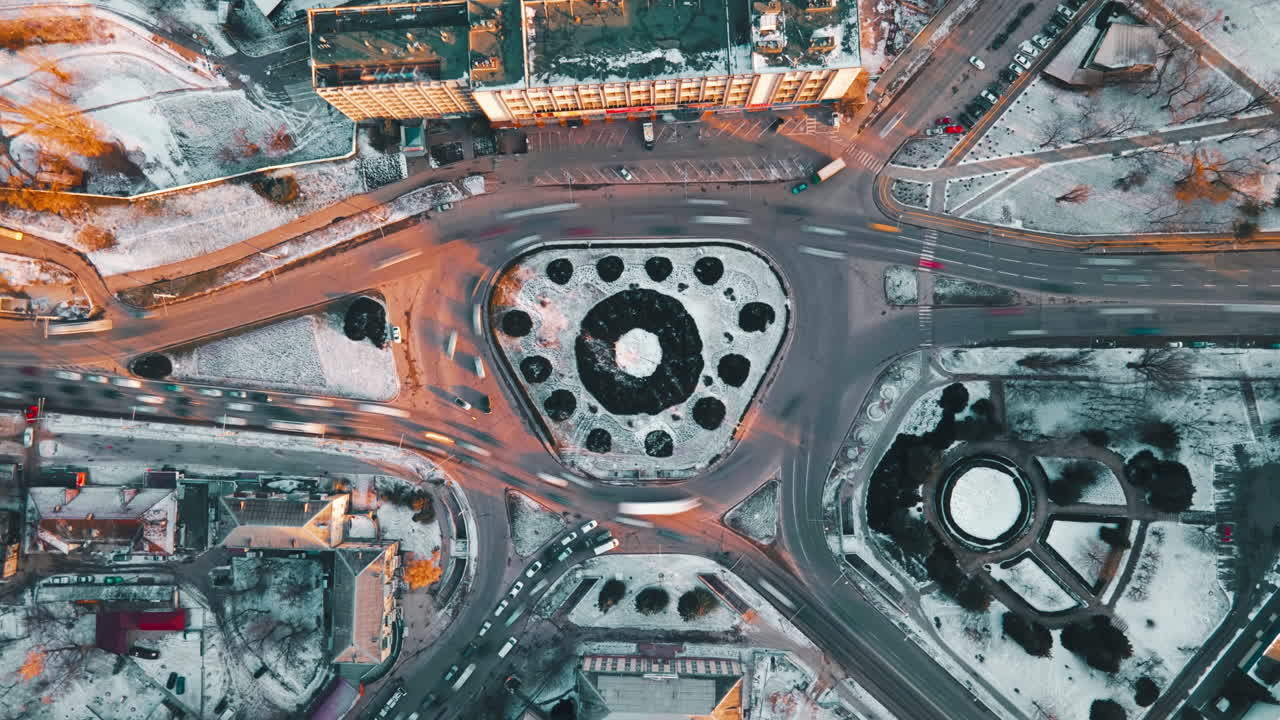 Hyperlapse of a roundabout intersection, drone view. Roads with moving cars, bare trees, snow on the ground. Chisinau, Moldova