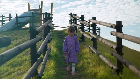 sad little girl walking down the hill trail with wooden fence at countryside playground