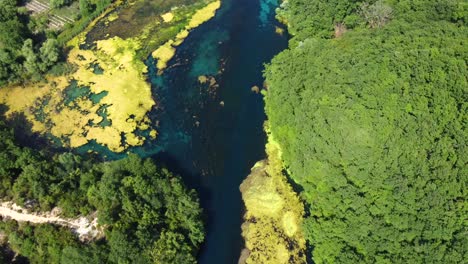 drone shot of the blue eye in albania - drone is following the river flow, showing its beautiful color and the clear water