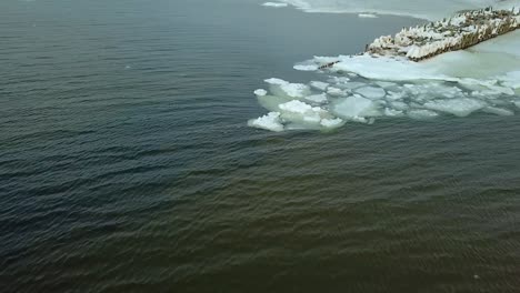 Big-Ice-Blocks-in-Sea-next-to-Snow-Covered-Pier---Aerial-View