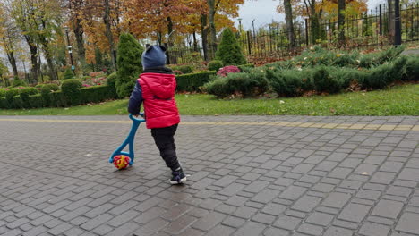 following the cute kid walking outdoors with his toy. baby boy running happily away from camera. autumn park at backdrop.