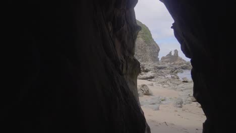 peak out of a cave to rock formation on the ocean at inverloch australia