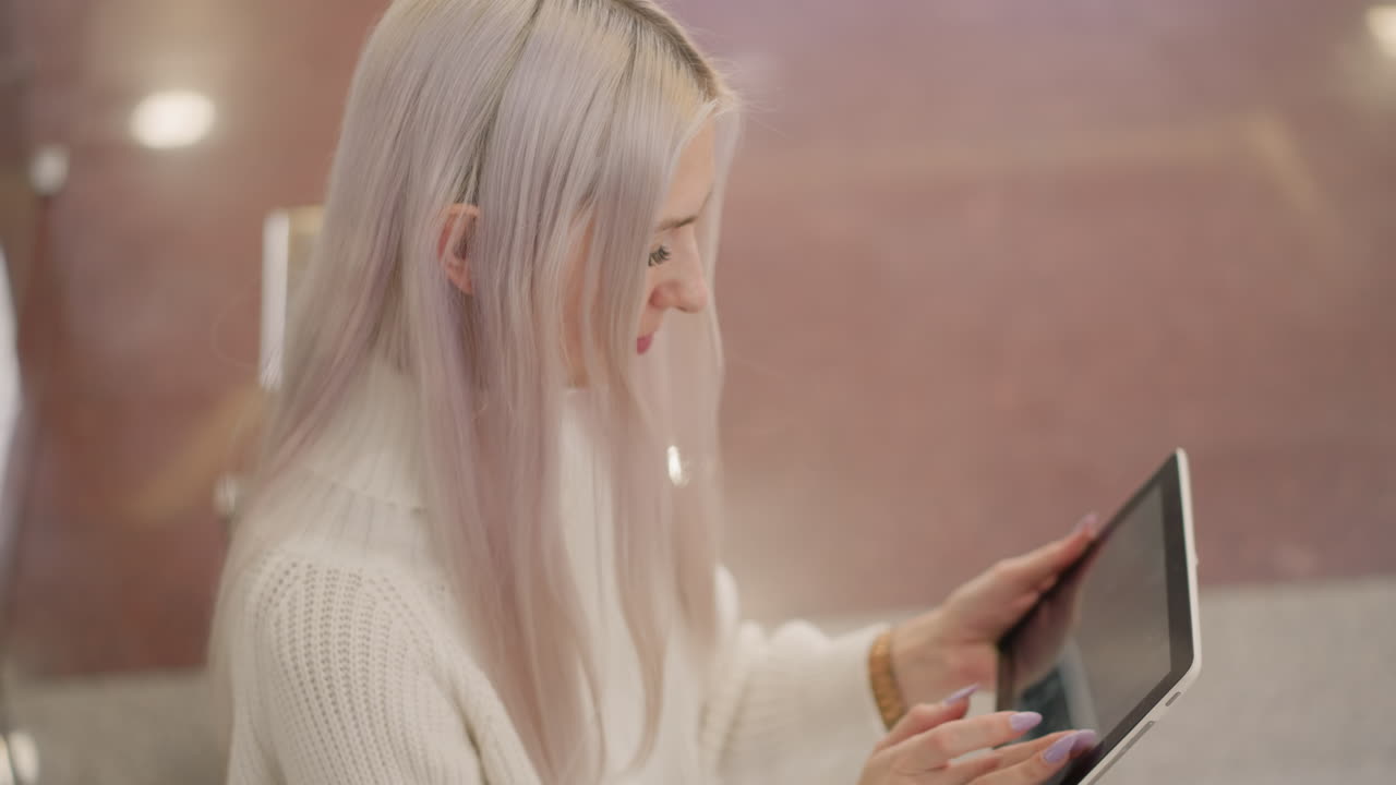 high angle view of shopper seated on bench using long lavender nails to tap glossy tablet screen, subtle mall floor background, refined digital interaction highlighting elegant manicure
