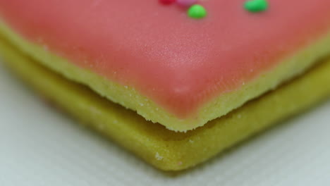 close-up macro center view of christmas cookies in the form of a pink heart with icing and decorated with colorful balls and its corpus in close up shot in slow motion capture