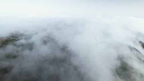 drone flight over wind generator rotors turning in clouds on madeira mountain