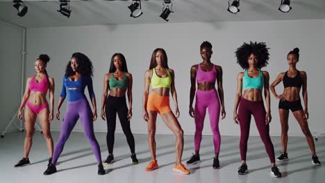 a diverse group of women in colorful athletic wear stand confidently in a studio