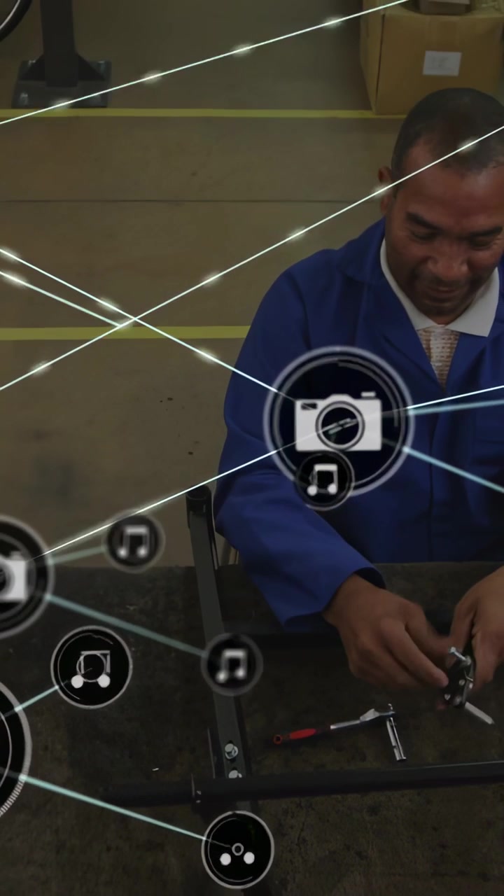 Assembling mature technician in blue work coat tightening small part at workshop, with HUD overlay