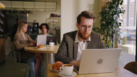 a man working on his laptop in a cafe.