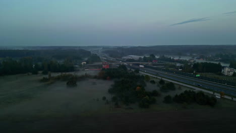 Temprano-En-La-Mañana-Niebla-Autopista-Tráfico-De-Coches-Ligeros-Cerca-Del-Bosque,-Aéreo