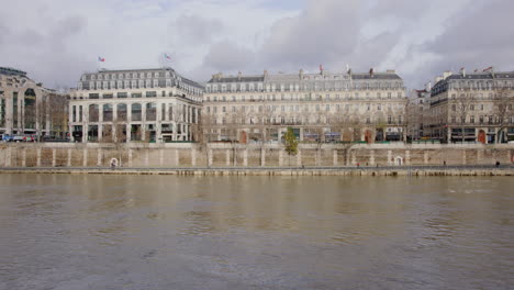 Wide-handheld-static-footage-of-joggers-running-on-the-sidewalk-next-to-the-Seine-in-Paris-France-during-winter