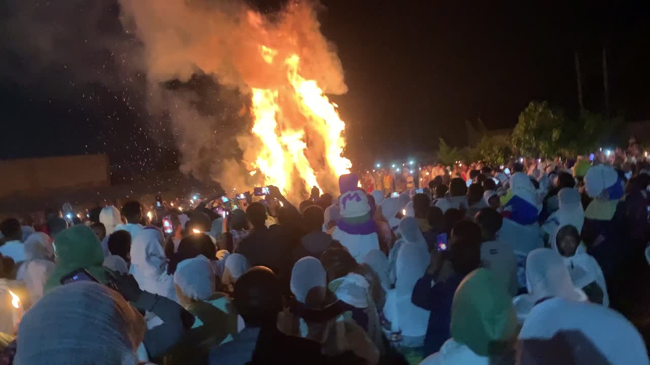 Large bonfire at night with a crowd of people celebrating