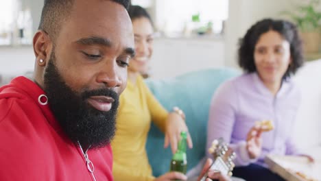 Happy-diverse-female-and-male-friends-playing-guitar-and-laughing-at-home-in-slow-motion