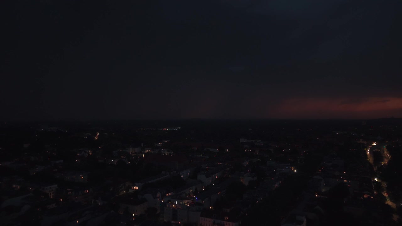 Fulmini che illuminano il cielo notturno scuro sopra gli edifici della città, catturando la potenza drammatica di un temporale estivo. Splendida panoramica aerea ripresa da drone.