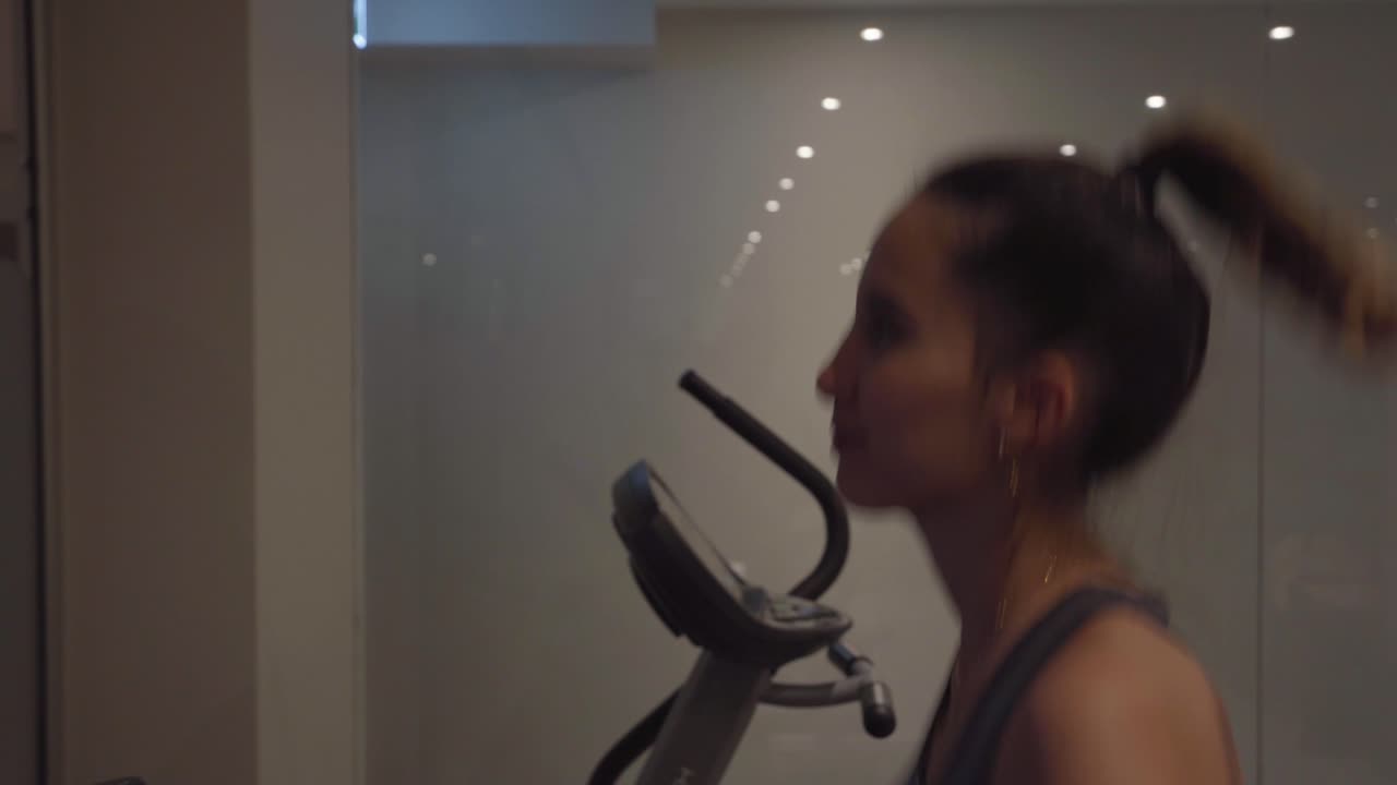 Young woman running on a treadmill inside a gym, concept for discipline and motivation