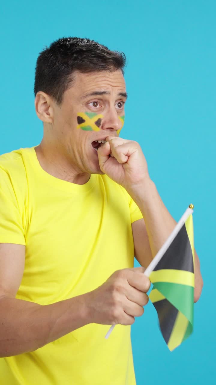 Nervous man cheering for Jamaica during a match looking away