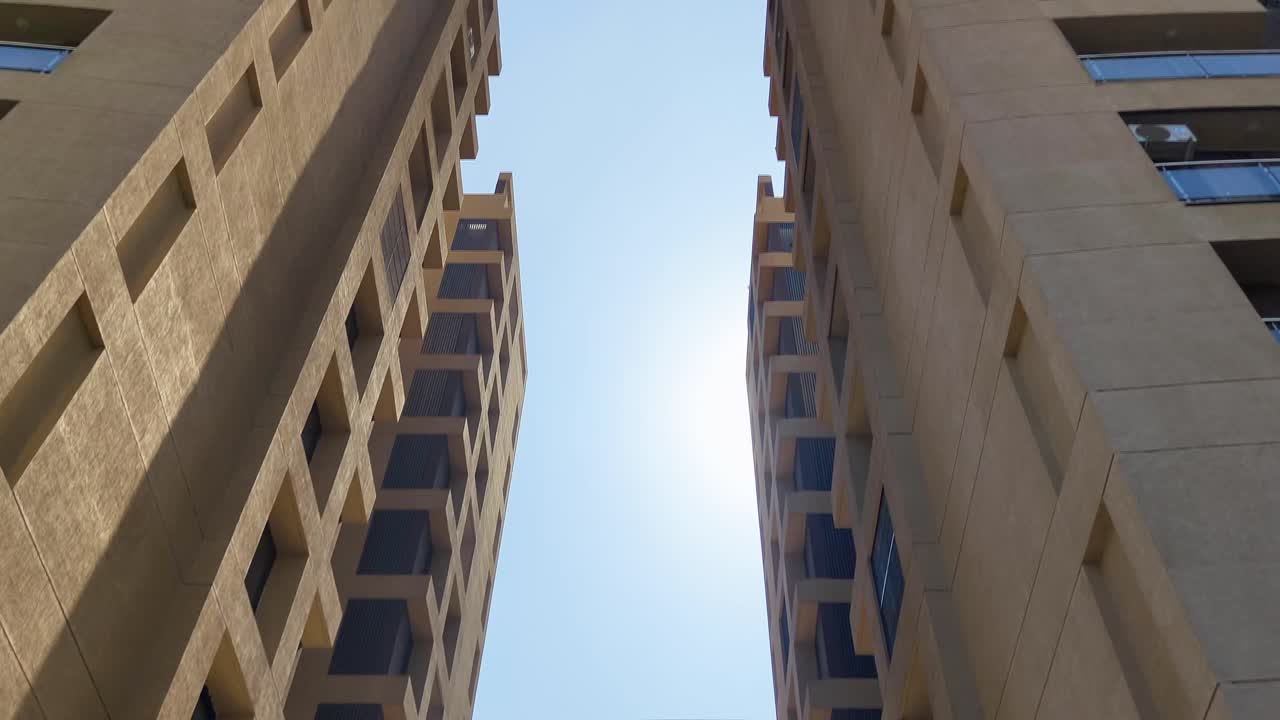 Tall modern architectural buildings with bright sunlit sky.
