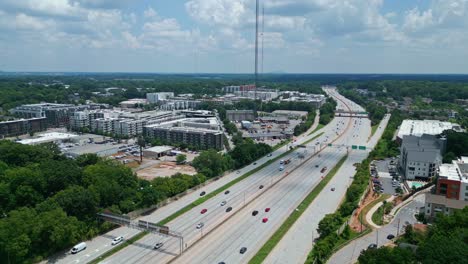 aerial view of atlanta highway suburb, bustling traffic and modern apartment complexes. lush greenery surrounds urban landscape, highlighting suburban living near the city. wide shot. sunny summer