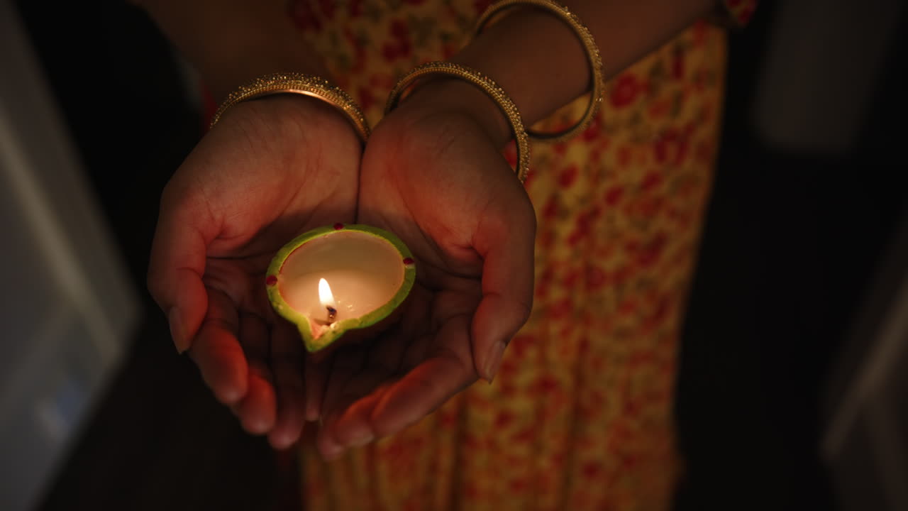 Holding lit diya, Indian woman celebrating traditional Indian festival in colorful sari