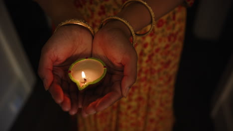 holding lit diya, indian woman celebrating traditional indian festival in colorful sari
