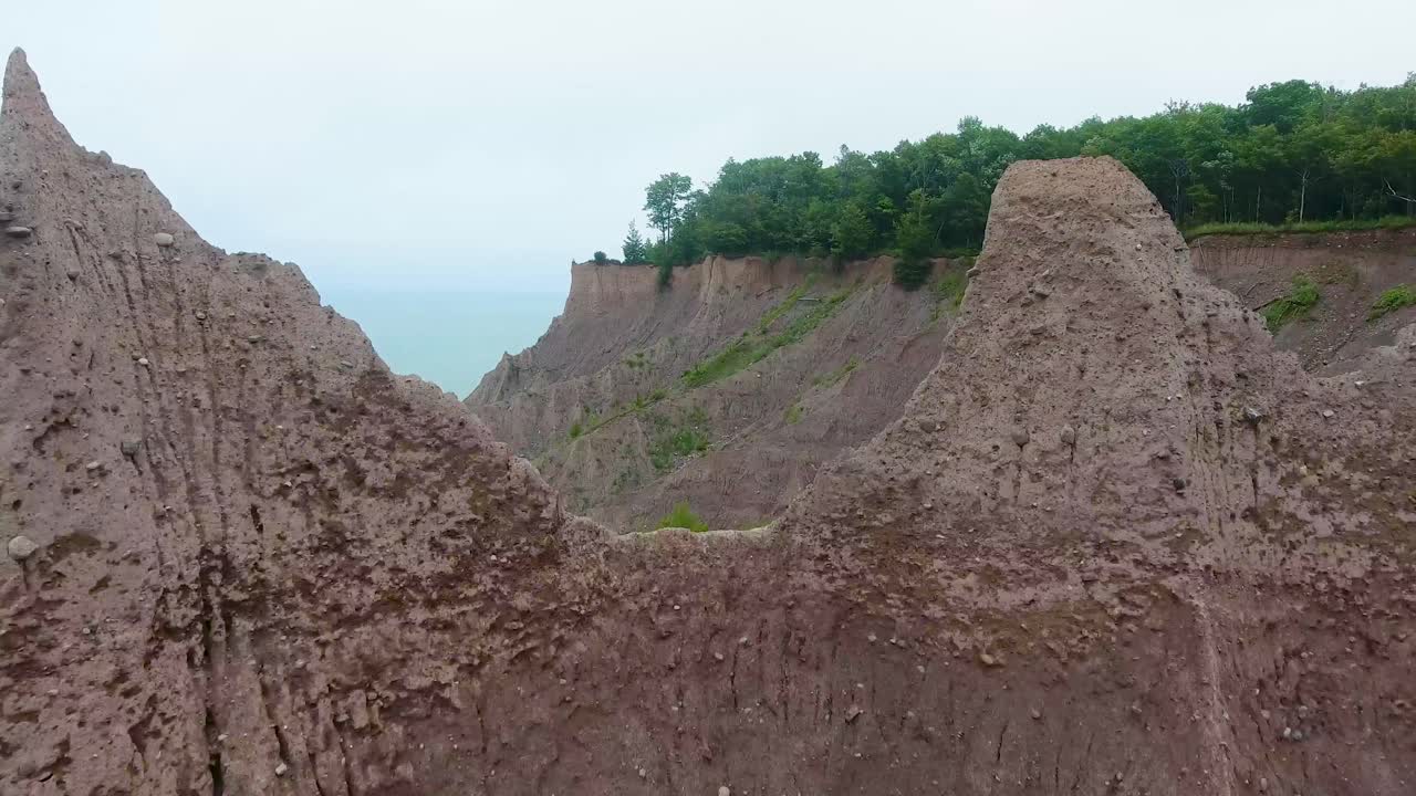 A 4K drone shot over the large clay formations of Chimney Bluffs State Park, on the water's edge of Lake Ontario, in the town of Huron, New York