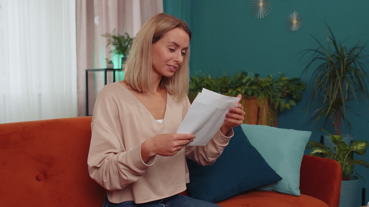 Pige åbner kuvertbrev, læser det og føler sig glad, karrierevækst, forfremmelse, godkendt banklån.