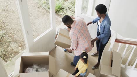 happy african american couple with son and daughter bringing boxes into house, slow motion