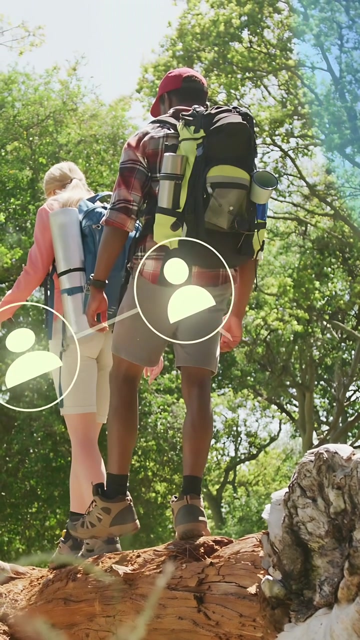 Video verticale: Due escursionisti appoggiano il piede su un tronco per attraversare un sentiero, con una sovrapposizione UI che evidenzia la parte bassa della schiena.
