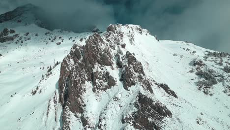 Orbit-drone-shot-of-the-snowy-and-jagged-slopes-of-the-Alpine-Mountains-in-Engelberg-in-Brunni,-Bahnen,-in-Switzerland