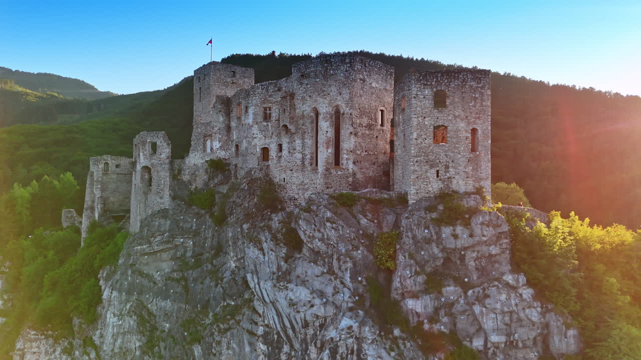 High rock with a castle on top. Drone footage around the scenery. Stunning verdant mountains at backdrop.