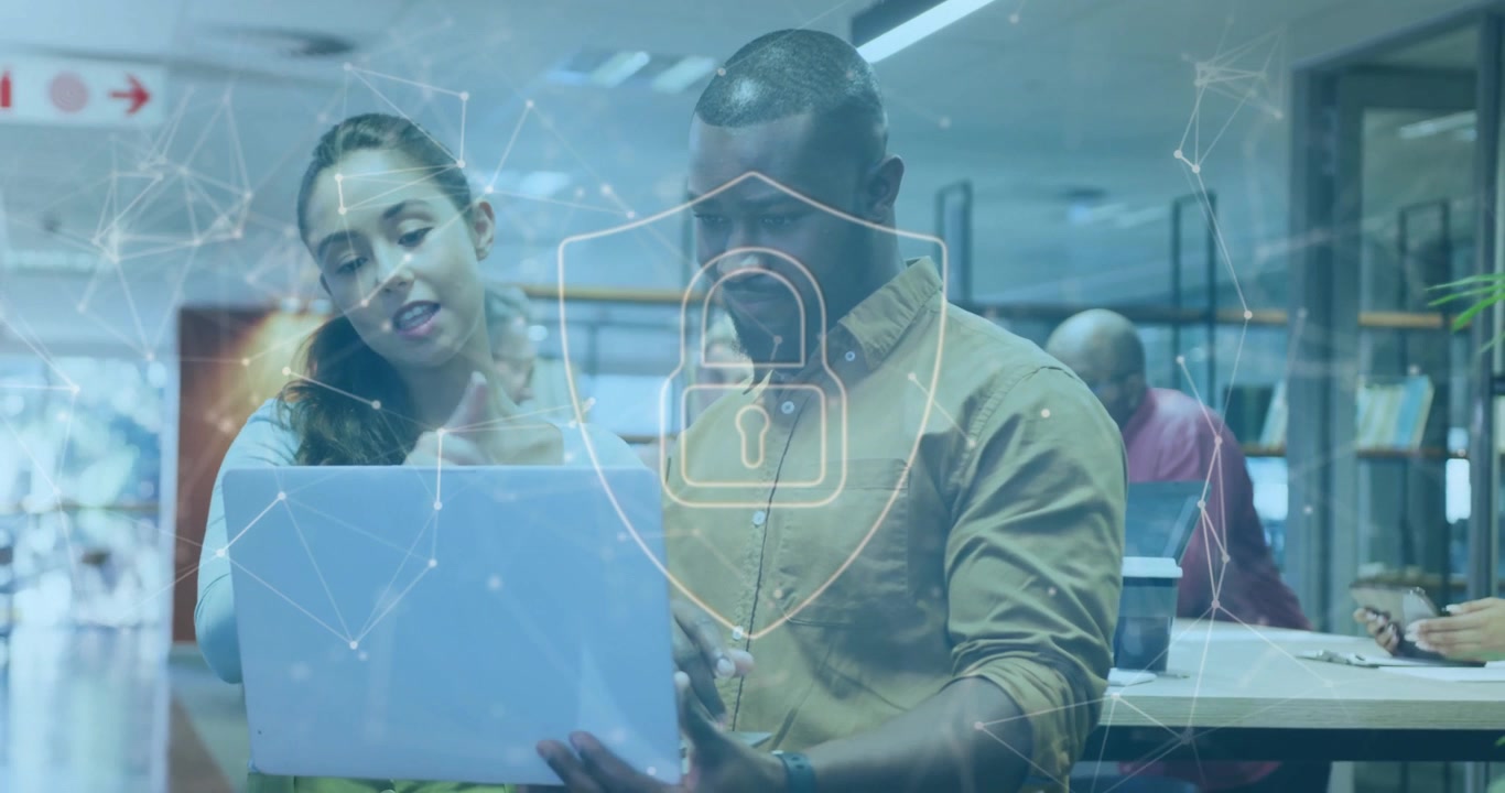 Woman pointing at laptop activating pulsing shield overlay, man scrolling explaining security