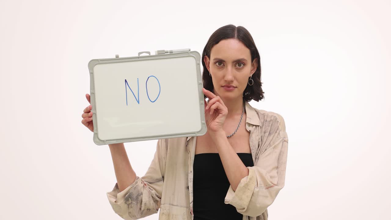 A woman holding a whiteboard with the word 'no' written on it