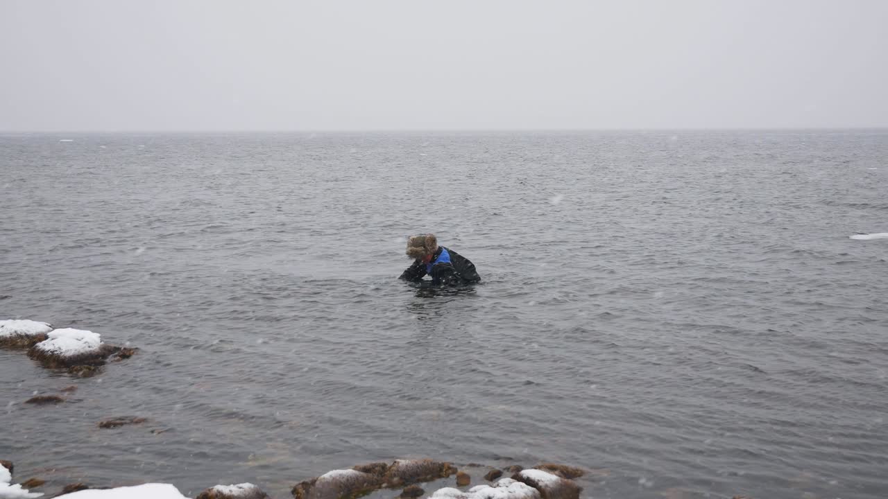 시망을 들고 있는 어부 는 겨울 에 해변 을 따라 걸어가며 맛 있는 음식 들 을 모으고 있다