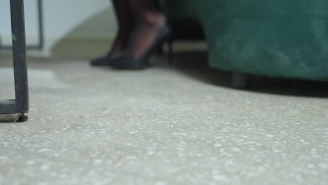 close up of woman leg in black stiletto heel as she walks across tiled office floor toward seat, showcasing elegant professional style and poised movement in workplace environment