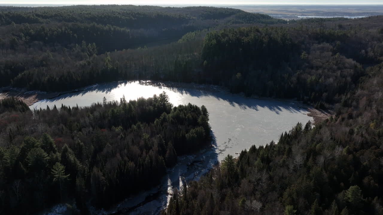 Luftfoto af sneklædt sø og skov i sensvinteren - droneoptagelse