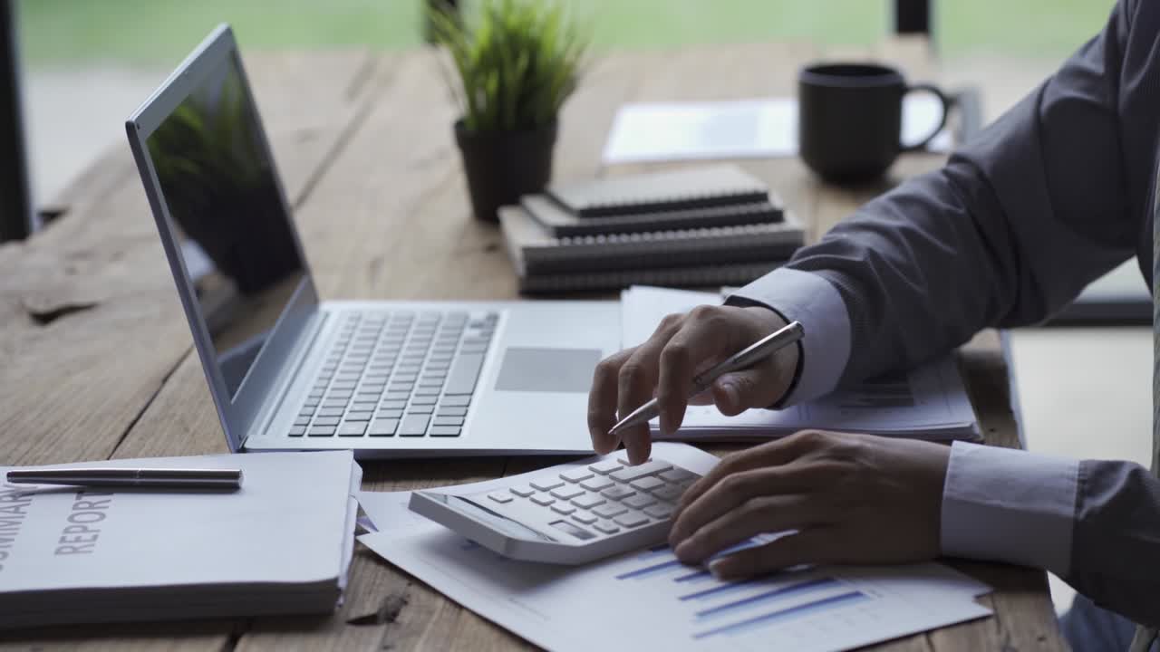 Businessman developing business project and analyzing marketing graph data with accounting documents and financial reports on 4k video table.