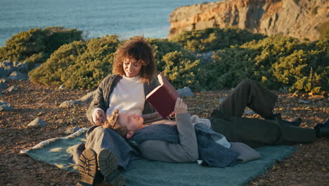 tranquil family reading book at nature spending weekend. man lying woman knees
