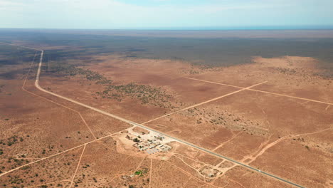 Aerial-view-of-a-autarkic-roadhouse,-powered-by-solar-power,-in-Australian-wasteland---tracking,-drone-shot