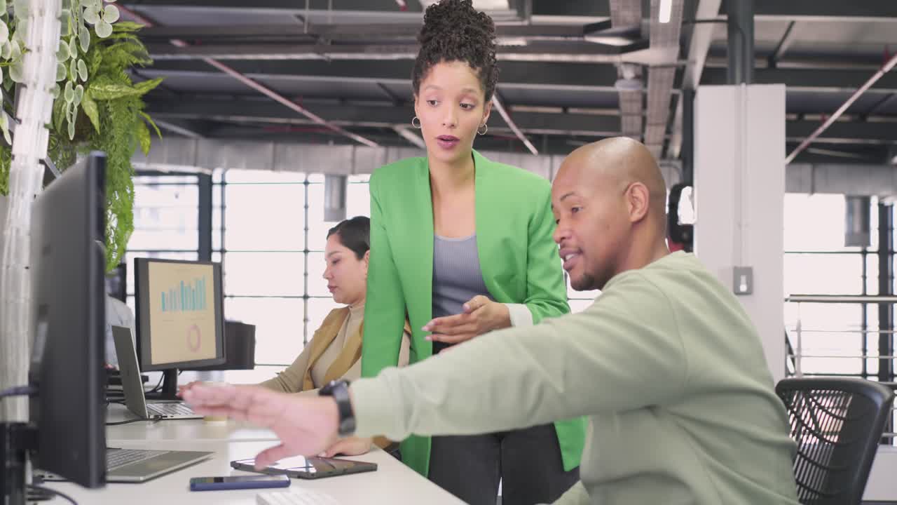 Pessoas diversas trabalhando no escritório, andando entre as mesas e discutindo gráficos de barras e de pizza para alinhar os objetivos