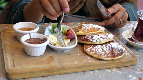 woman eating pancakes with fruit and chocolate