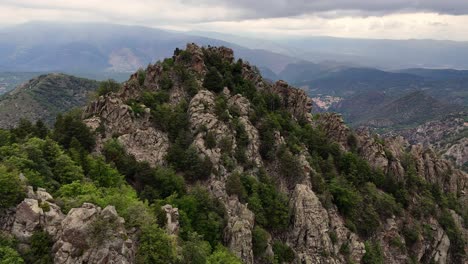 Drone-footage-of-a-rocky-peak-and-a-green-forest-in-the-Pyrenees-mountains