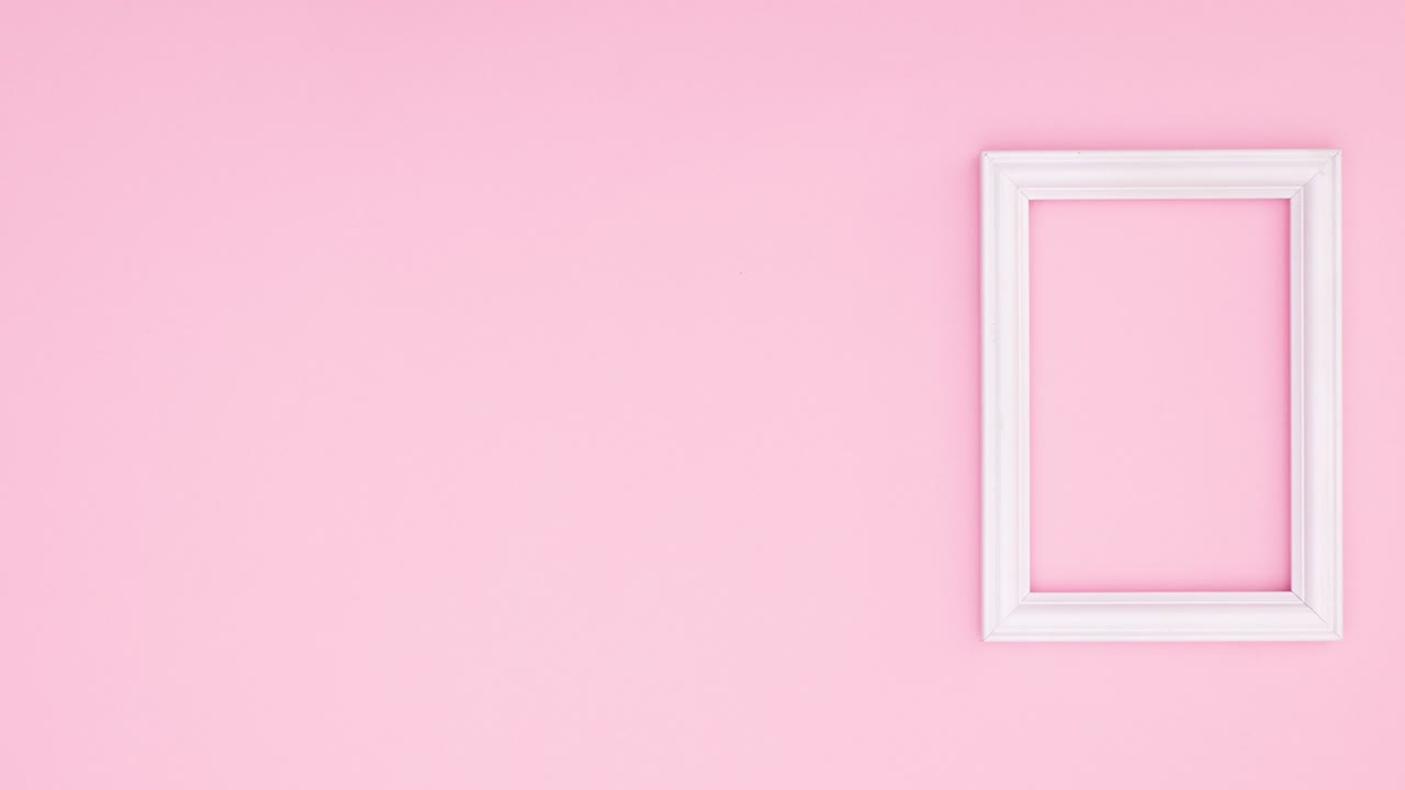 Hoja verde cayendo junto a un marco blanco romántico sobre un tema rosa. Stop motion