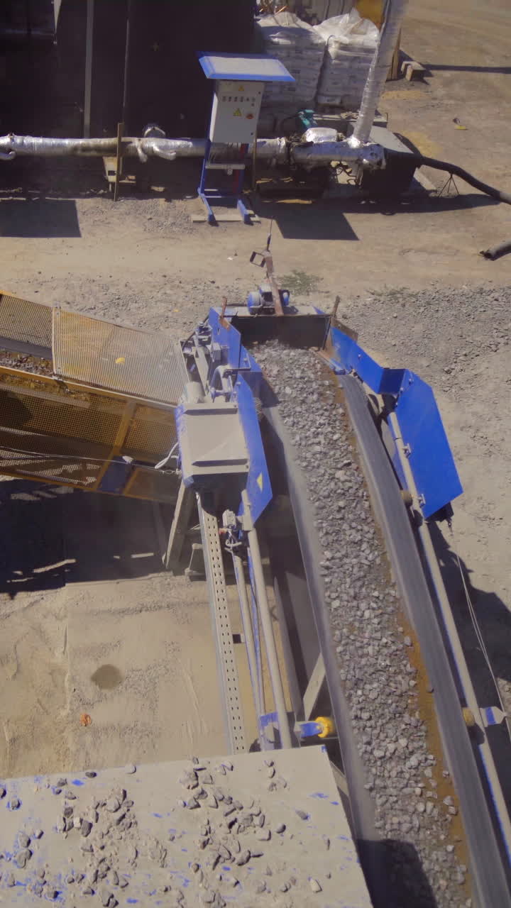 Asphalt plant outdoors. Aerial view on the modern equipment for asphalt production. Gravel moves up on conveyor. Vertical video