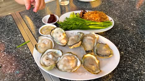 hand arranging oysters with garnishes on plate