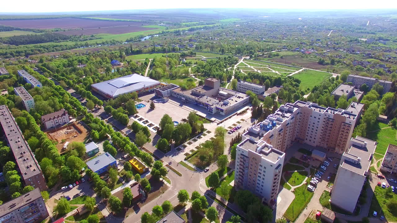 Big green city with residential areas and large shopping malls. Sunny view of the city in summer. Aerial perspective.