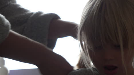 getting ready for kindergarten daily routine, mother combing hair of young girl