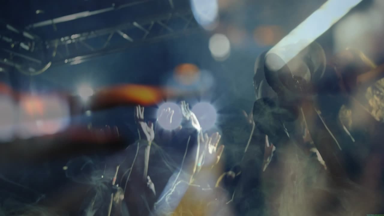 Crowd raising hands and crowd surfing cheering to music, finger passing lens creating bokeh flares